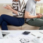 ludzie siedzący do siebie plecami liczący pieniądze